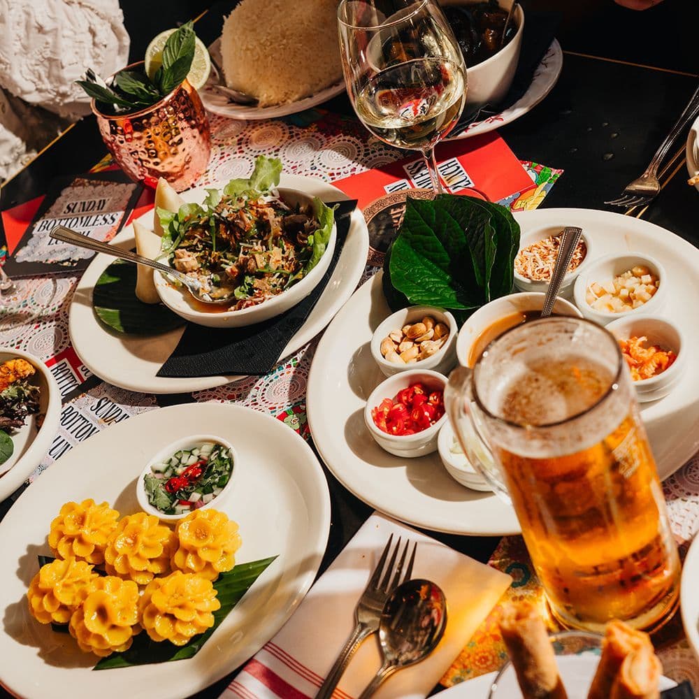 A bustling table laden with a variety of Thai dishes, beer, and wine.