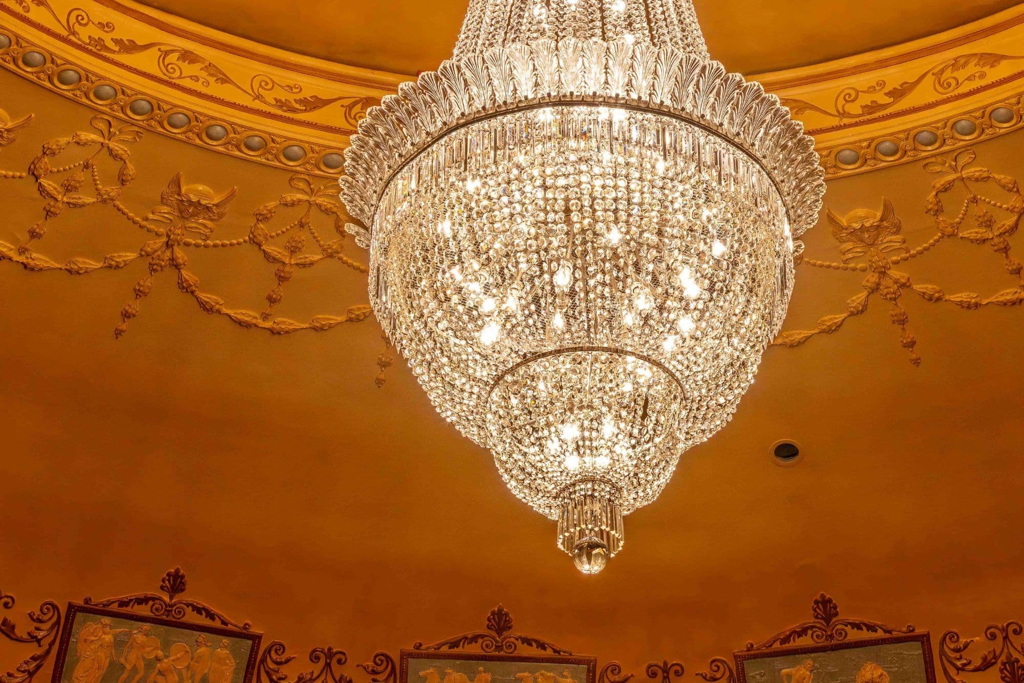 A large, multi-tiered crystal chandelier hangs from an ornate golden ceiling.